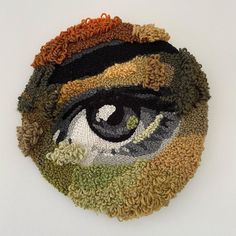 a close up of an eye made out of knitted material on a white surface