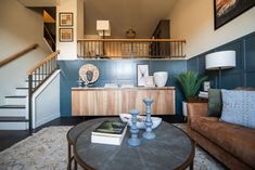 a living room filled with furniture and a stair case next to a coffee table on top of a rug