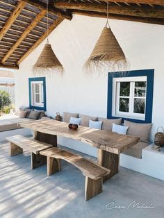 a wooden bench sitting under three hanging baskets on the ceiling next to a table with two benches underneath it