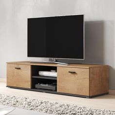 a flat screen tv sitting on top of a wooden entertainment center next to a wall