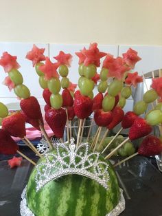 a watermelon crown with grapes and strawberries in it on a black table