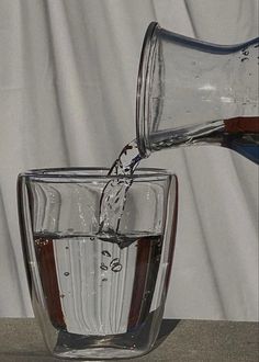 a glass filled with water being poured into it