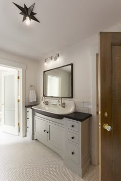 a bathroom with a sink, mirror and two lights on each side of the door