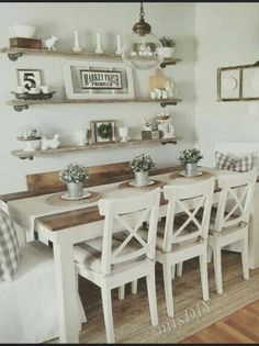 the dining room table is set with white chairs and place settings on shelves above it