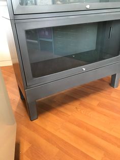 a microwave oven sitting on top of a hard wood floor next to a cabinet with glass doors