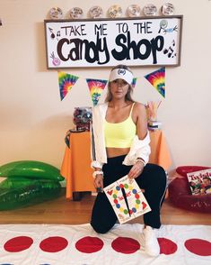 a woman sitting on top of a bed in front of a candy shop sign