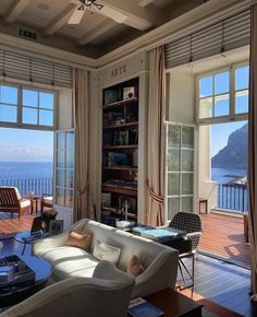 a living room filled with furniture and large windows overlooking the ocean in front of it