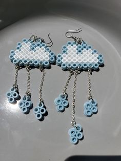 two pairs of blue and white beaded earrings hanging from chains on top of a plate