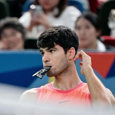 a male tennis player holding his racket up to his mouth