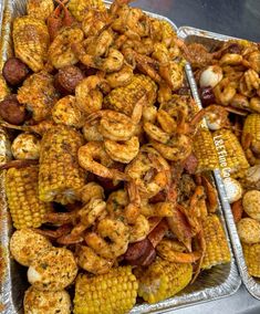 two trays filled with shrimp and corn on the cob next to each other