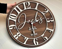 a wooden clock with the words jack's bar on it and hands holding it