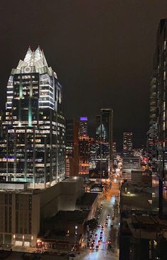 the city skyline is lit up at night, with tall buildings in the foreground