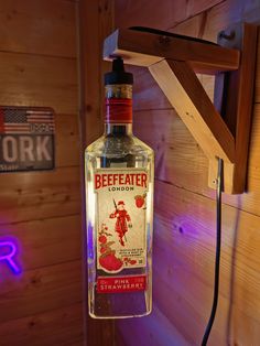 a bottle of beefeater london gin on a hook in the corner of a wood paneled room