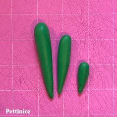 three green plastic objects sitting on top of a pink surface