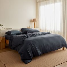 a large bed sitting in a bedroom next to a wooden dresser and window with curtains