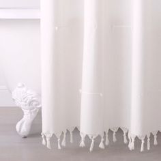 a white shower curtain with tassels hanging from it