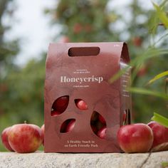 a bag of honey crisp sitting on top of a stone wall next to some apples