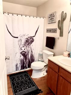 a bathroom with a cow shower curtain and rug