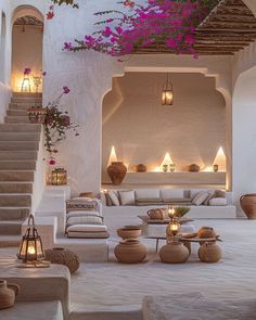 a living room filled with lots of furniture and flowers hanging from the ceiling above it