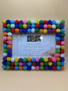 a multicolored photo frame with pom - poms on the front and bottom