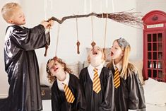 a group of kids dressed up in harry potter costumes with brooms and wands hanging from strings