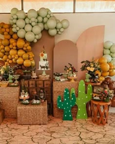 a dessert table with cactus decorations and balloons