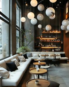 a living room filled with lots of white couches and round lights hanging from the ceiling