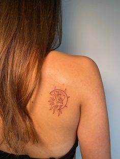 the back of a woman's shoulder with a small tattoo on her left arm