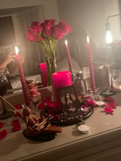 a table topped with candles and pictures next to pink roses on top of a table