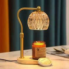 a table with a candle and a glass jar on it next to a gold lamp