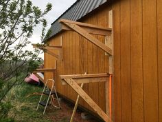 the side of a wooden barn with a metal roof and ladders next to it