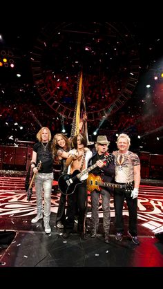 a group of people standing on top of a stage with guitars and microphones in their hands