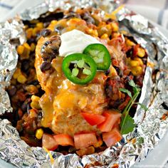 an enchilada covered in cheese, black beans, corn and sour cream