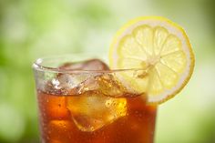 a close up of a drink in a glass with ice and lemon