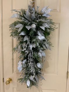 a wreath hanging on the front door of a house decorated with silver and white decorations