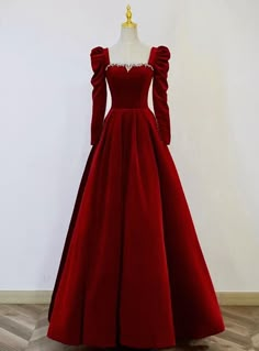 With this prom dress, the evening becomes an event of regal splendor. The gown's deep red velvet is a striking statement of both passion and refinement, while its fitted bodice, embellished with an intricate pattern of crystals, shines with an understated elegance. The puffed sleeves, a nod to the romantic styles of yesteryear, frame the arms with a dramatic poise, and the sweeping skirt creates a silhouette that is both commanding and graceful. This dress is an invitation to step into a world of sophistication and to embrace a night of unforgettable memories, all while draped in the epitome of prom perfection. Red White Prom Dress, Red Winter Wedding Dress, Royal Night Gown, Plain Net Gown Designs Latest, Red Gown Elegant Classy, Red Gown With Sleeves, Red Wedding Gowns Brides, Red Masquerade Dress, Velvet Gowns Evening Dresses