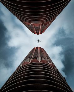 an airplane is flying through the sky between two tall buildings in front of a cloudy blue sky