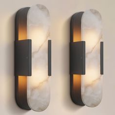 two lights that are next to each other on a wall with marble and metal accents