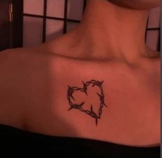 a woman with a tattoo on her shoulder that has barbed wire in the shape of a heart