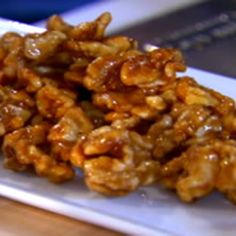 a pile of walnuts sitting on top of a white plate next to a wooden table