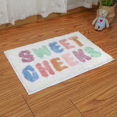 a welcome home rug on the floor next to a teddy bear and potted plant