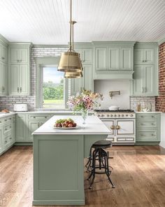 a large kitchen with green cabinets and white counter tops, along with a breakfast bar