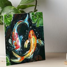 two colorful koi fish swimming in the water art boarder on a table next to a potted plant