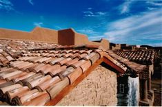 the roof of an old adobe building with water running down it's side and blue sky in the background