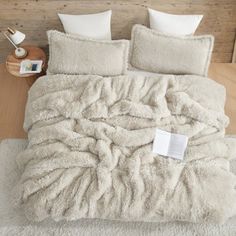 a bed covered in white fluffy blankets and pillows