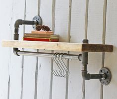 a shelf with some books on it next to a wall mounted clock and pipe pipes