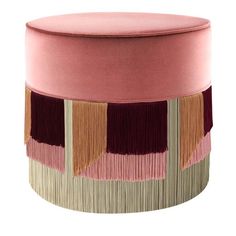 a pink ottoman with fringes on the top and bottom, sitting in front of a white background