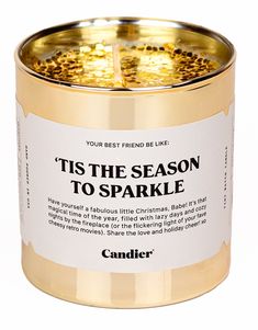 a candle that says tis the season to sparkle in gold and white with black speckles