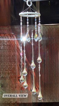 a wind chime hanging from the side of a wooden fence with crystal beads on it