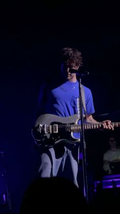 a young man is playing the guitar on stage